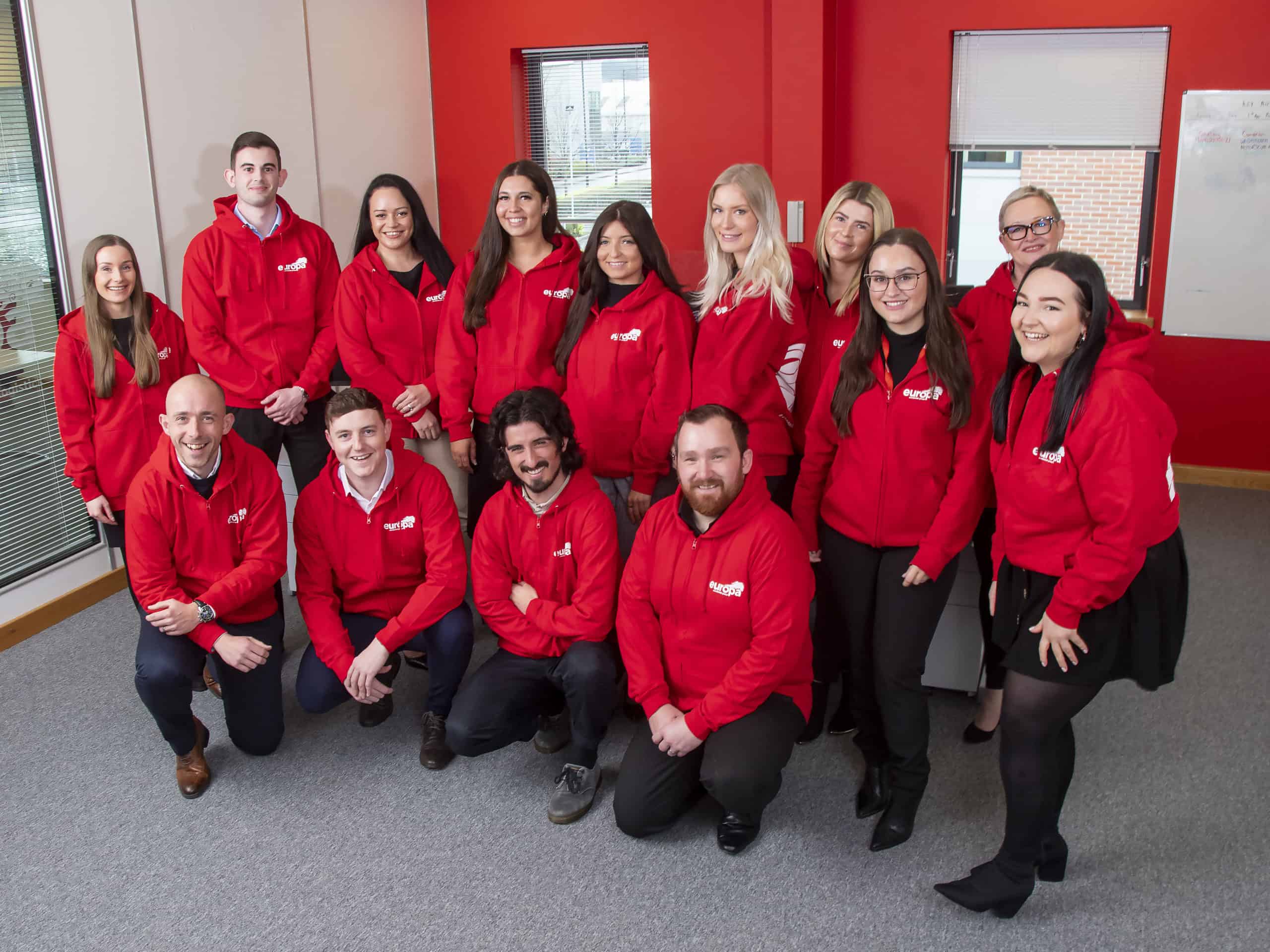 The Europa Road Team in Sheffield smile together in red Europa branded hoodies