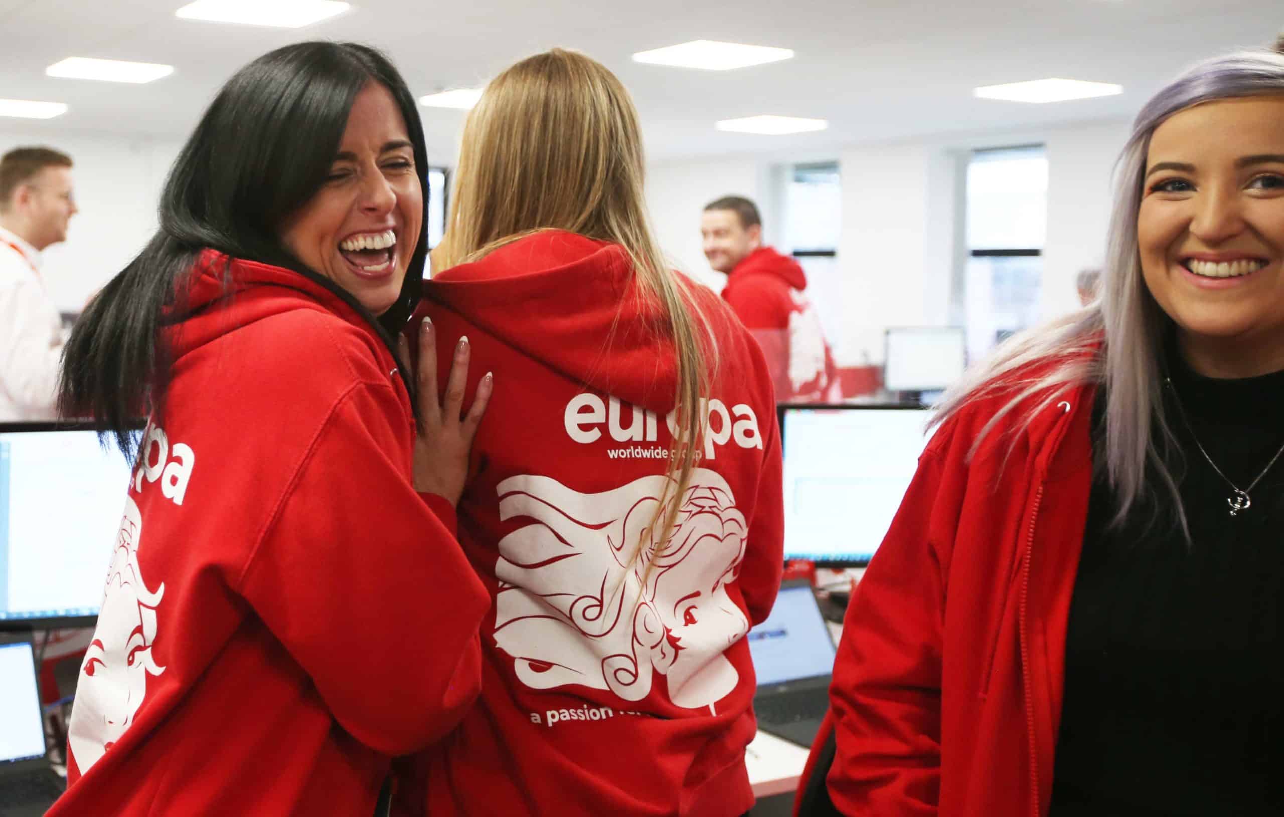 Europa Road Newcastle team member laughs in branded red, Europa hoodie